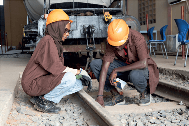 Deux techniciens en casque de chantier inspectent une voie ferrée.