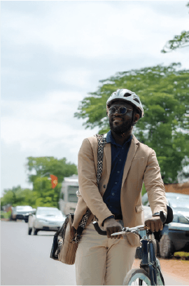 Un homme en costume traverse la ville à vélo, casque sur la tête.